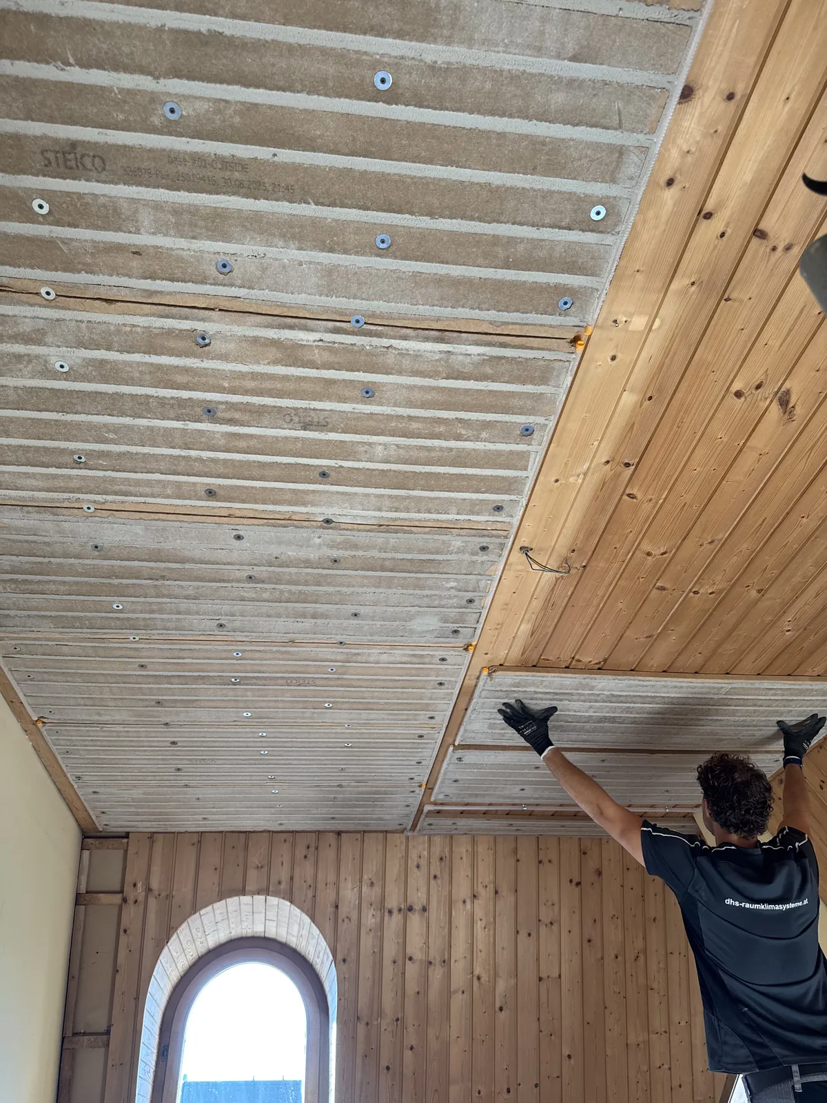 Vorher: Ein DHS-Monteur setzt Klimaplatten direkt auf die alte Holzdecke im Dachgeschoss
